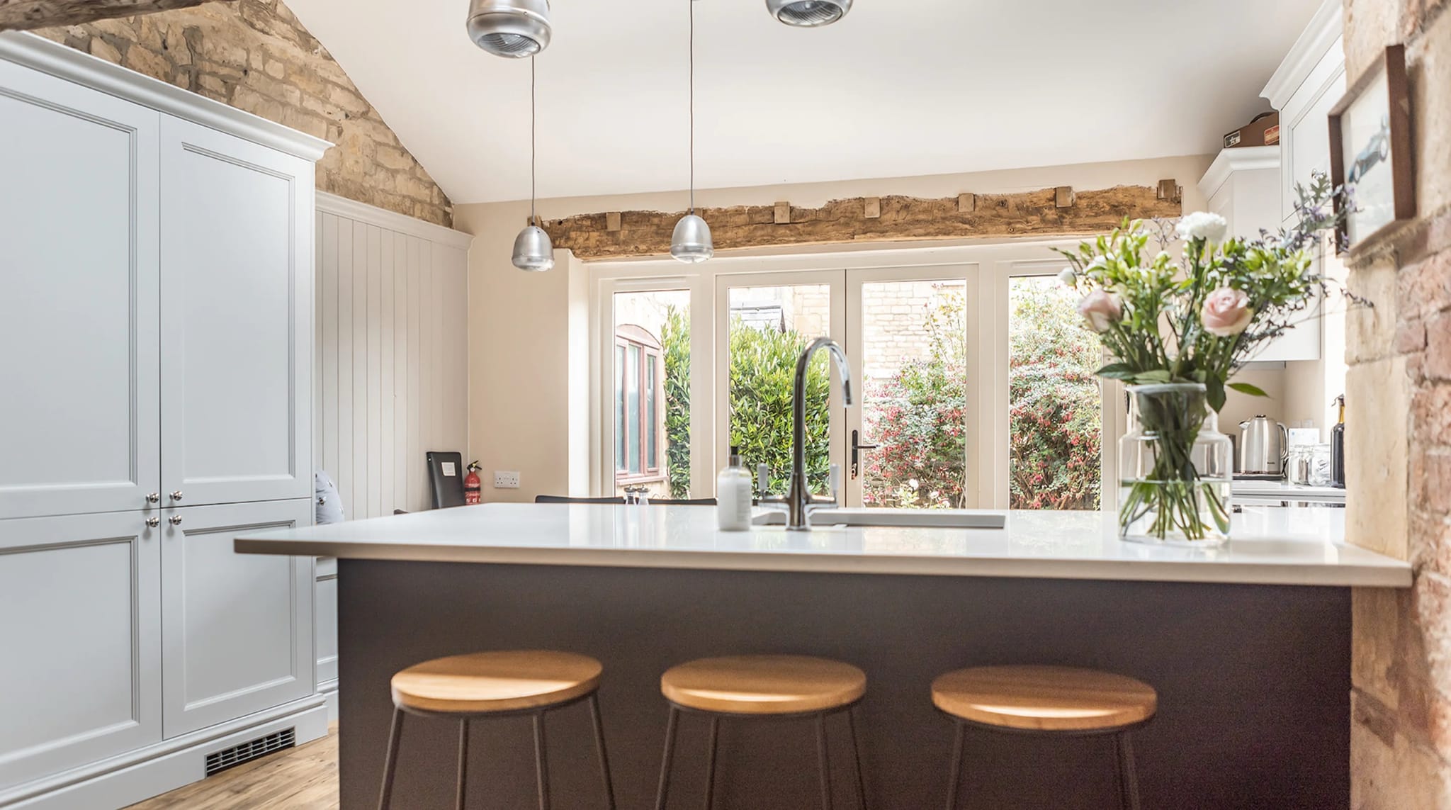 Bright kitchen with a breakfast-bar island and French doors to the garden